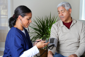caregiver checking senior man's blood pressure