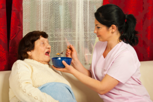 caregiver assisting senior woman in eating